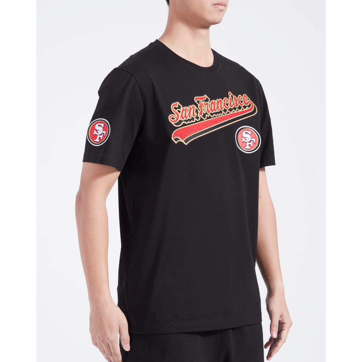 Close-up of the black Pro Standard 49ers T-shirt featuring bold red and gold script and tail logo on front