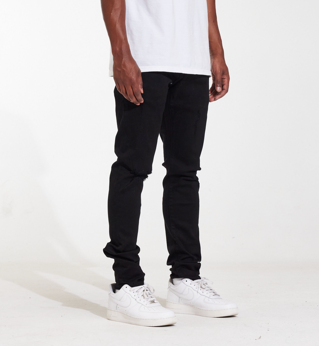 Model wearing the Crysp Denim Atlantic Black Ripped Denim Jeans with a white t-shirt and sneakers, showcasing the fit