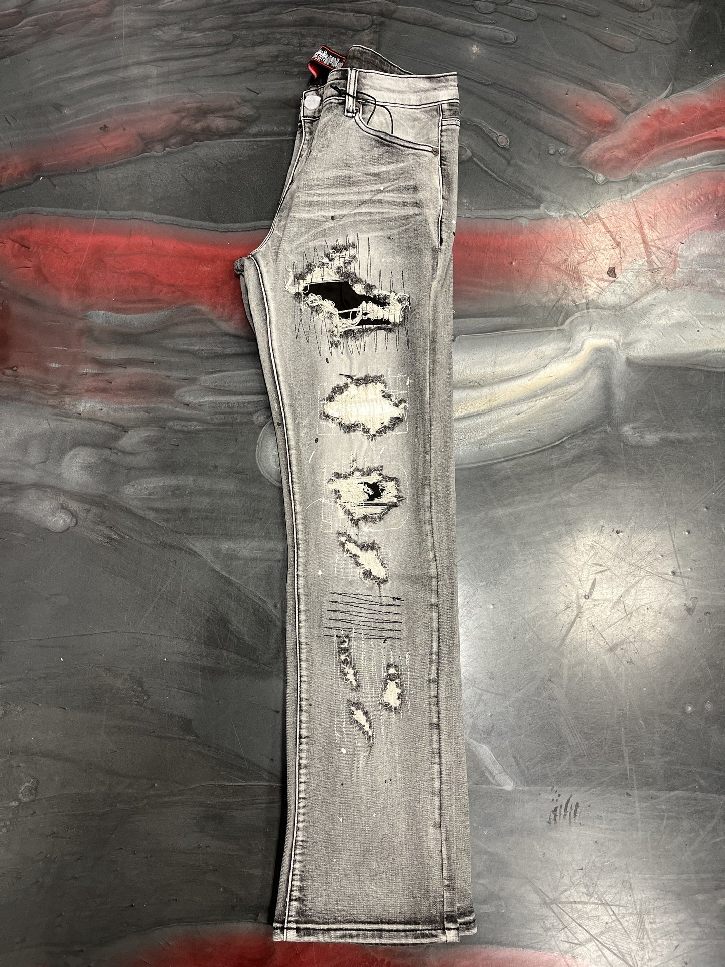 Close-up image of DENIMiCITY Rip & Repair Grey Wash Denim with black stitches, style DNM-K079, showcasing distressed detailing and modern urban design