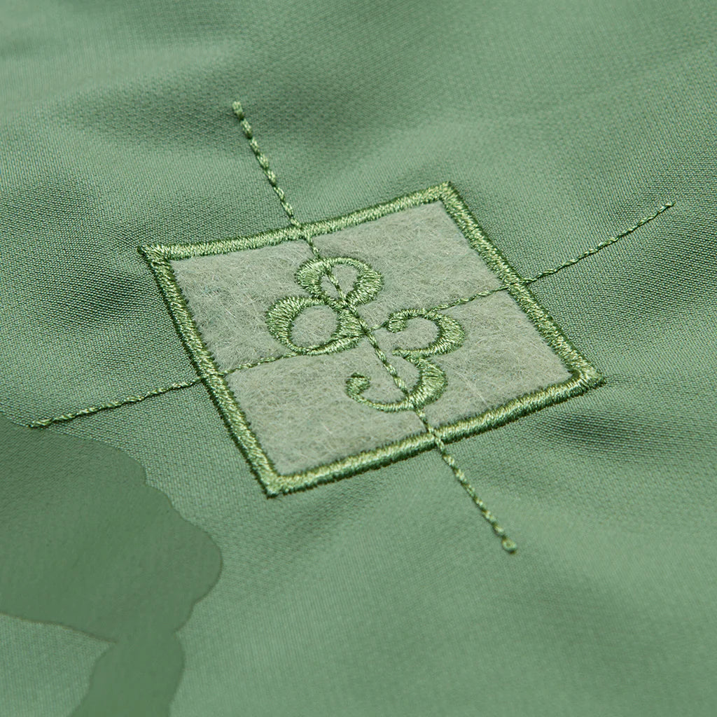 Cookies Key Largo Light Olive Swim Shorts folded and placed on a beach towel next to a pair of sandals