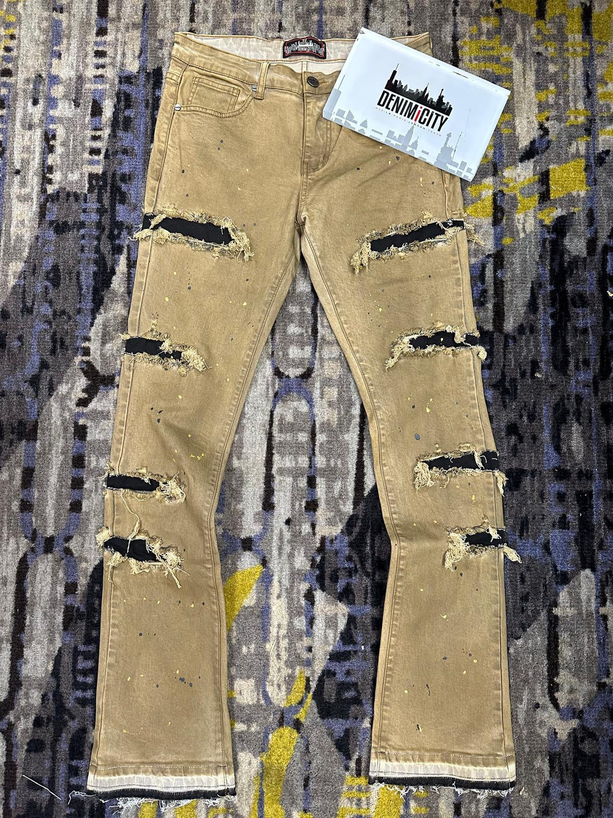 Close-up image of DENIMiCITY Zombie Ripped Gold Mechanic Wash Denim - Black (DNM-K115) showcasing distressed detailing and gold hardware on black denim fabric