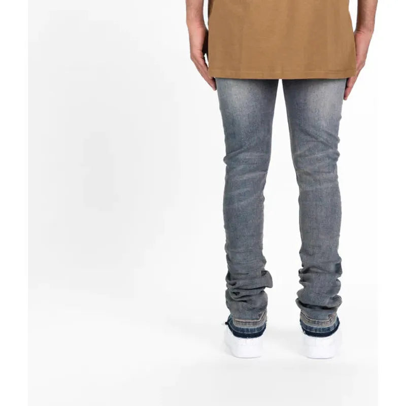 Side view of a model wearing PHEELINGS Now Or Never Medium Rust Blue Flare Stack Denim with a graphic tee and sneakers