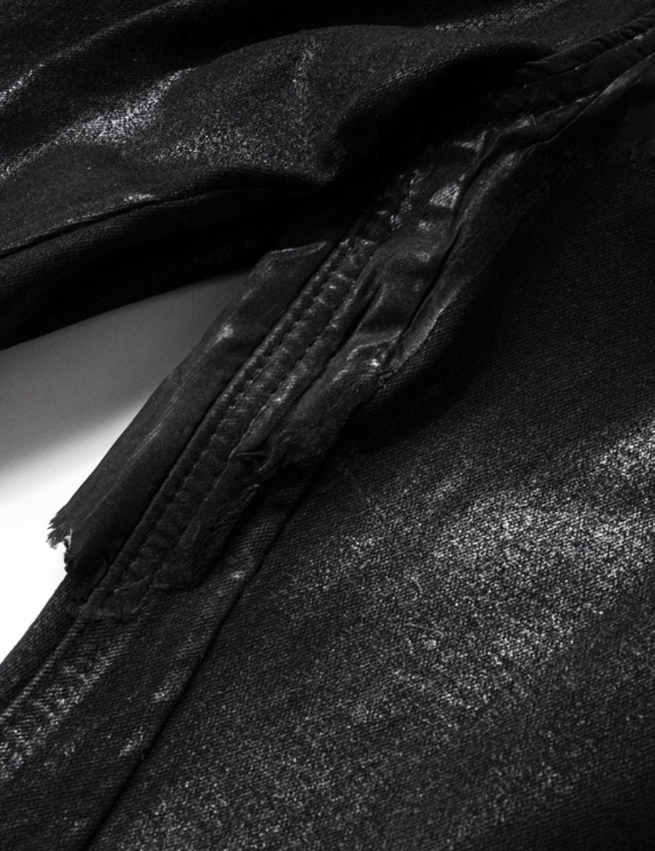 Rear view of black denim jeans highlighting patchwork design and waxed textured surface