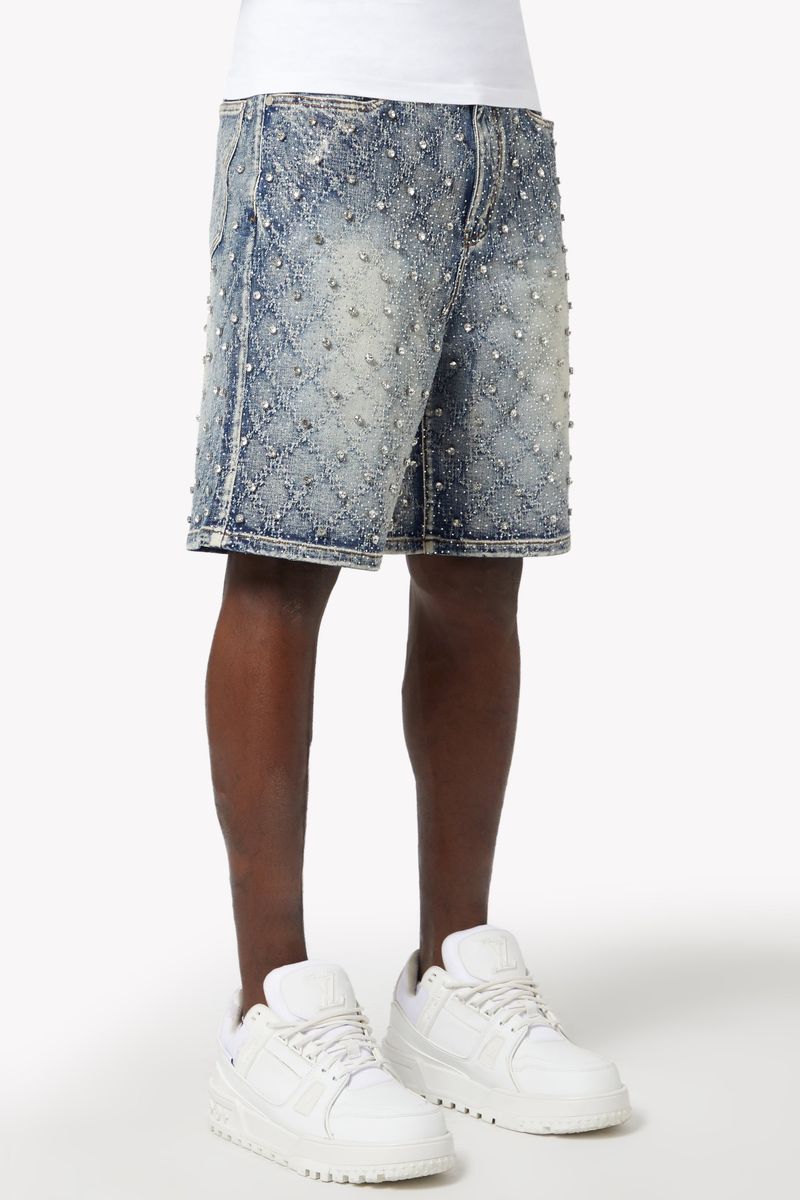 Mid-length distressed denim shorts featuring shimmering embellishments and vintage-inspired faded effects