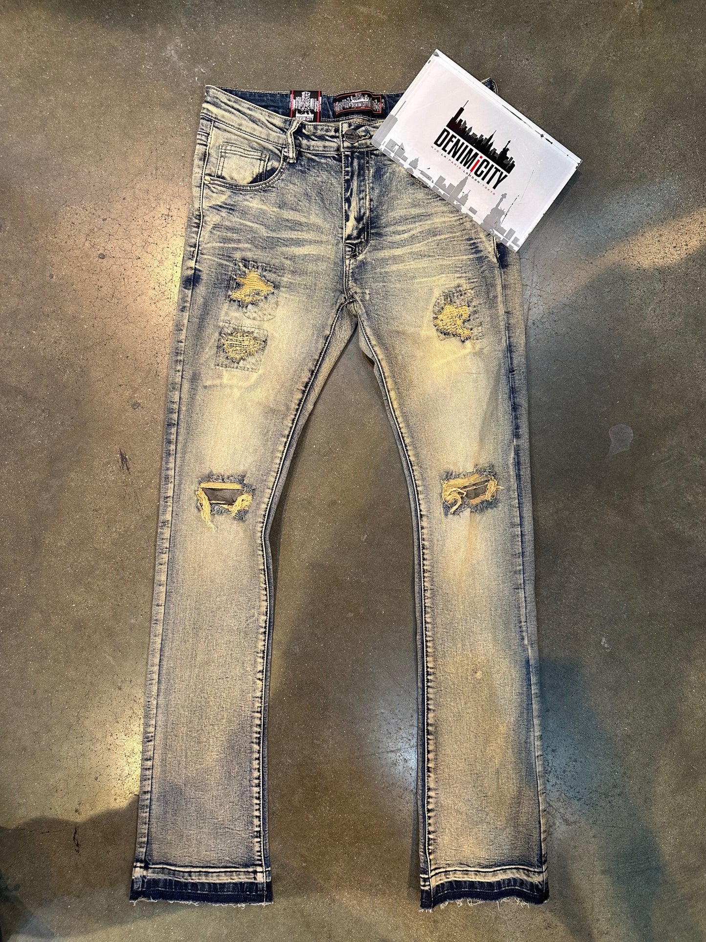Dark vintage wash stacked denim with knee rip and bleached details