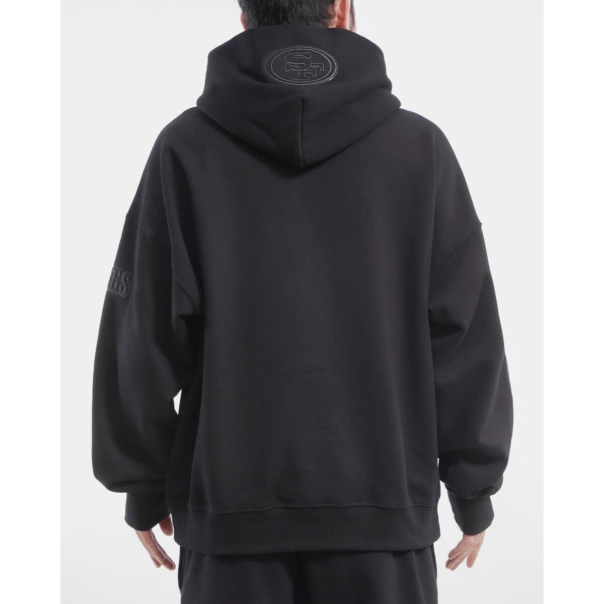 Close-up of the black Pro Standard hoodie featuring San Francisco 49ers branding on the front in a drop shoulder design