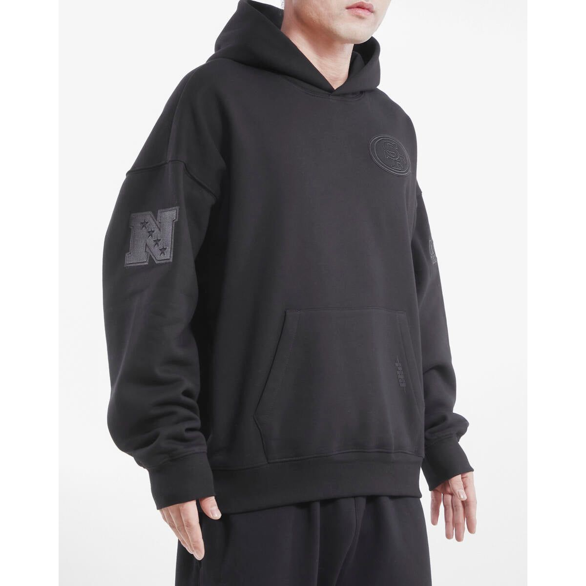 Side angle highlighting the drop shoulder construction and soft fabric of the San Francisco 49ers hoodie in black