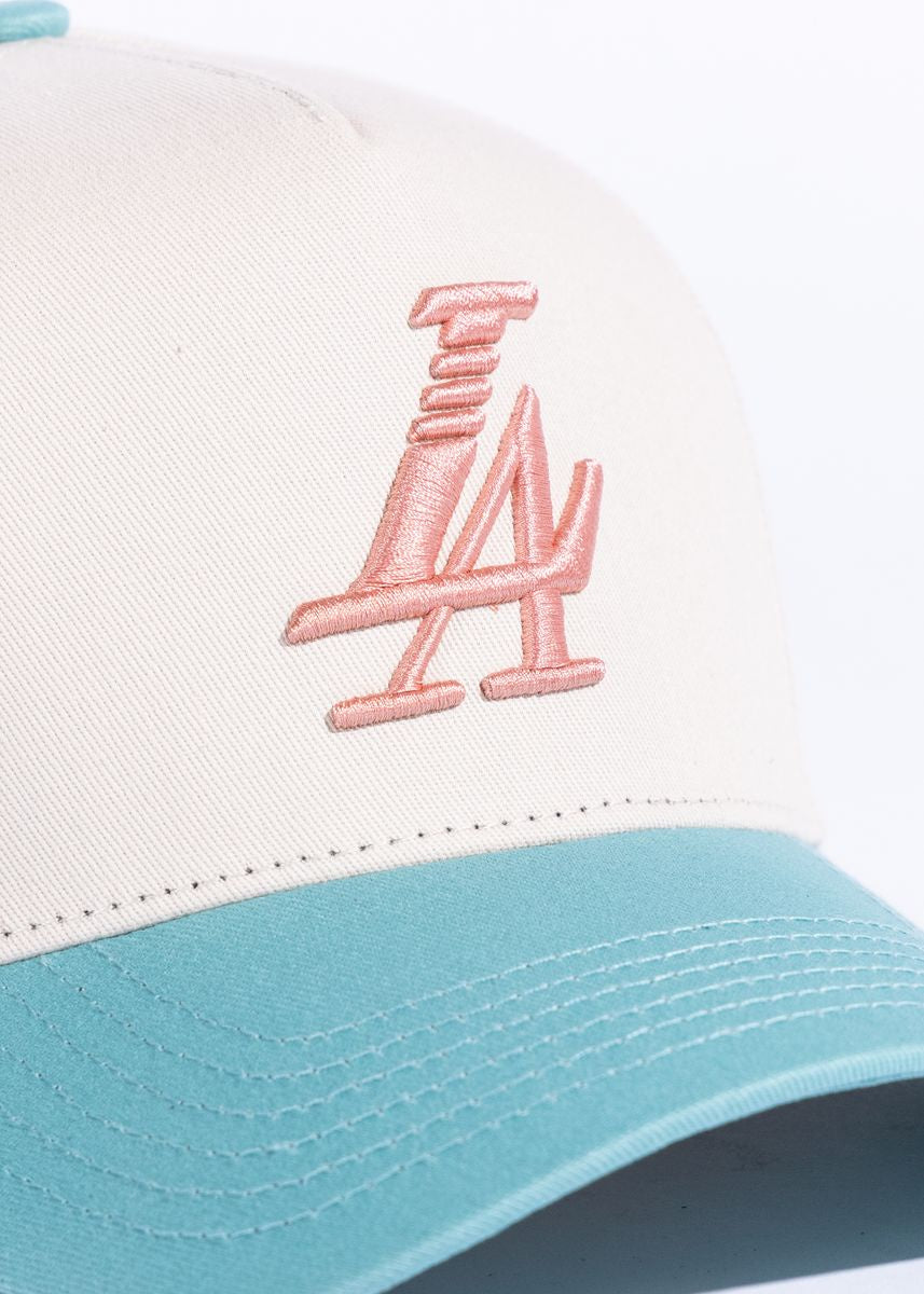 Close up of cream, teal, and pink Paradise LA Snapback Hat with embroidered logo on the front and adjustable strap at the back