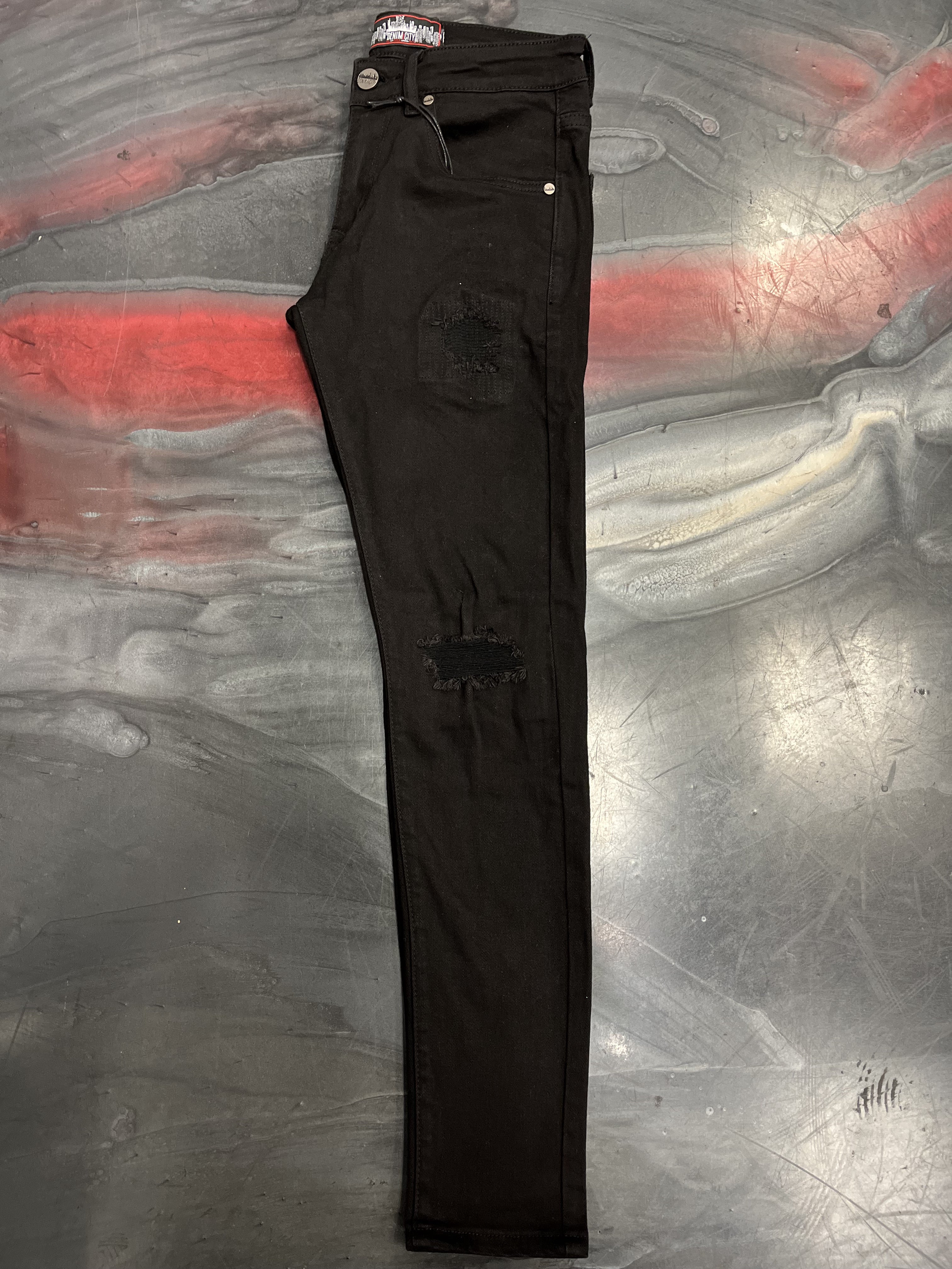 Close-up image of DENIMiCITY Knee Rip Jet Black Skinny Denim showcasing distressed knee rips and sleek jet black color (DNM-001JETBLACK)