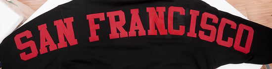Lifestyle image of a woman wearing the black Pro Standard San Francisco 49ers Wingspan Women's Crewneck in casual setting