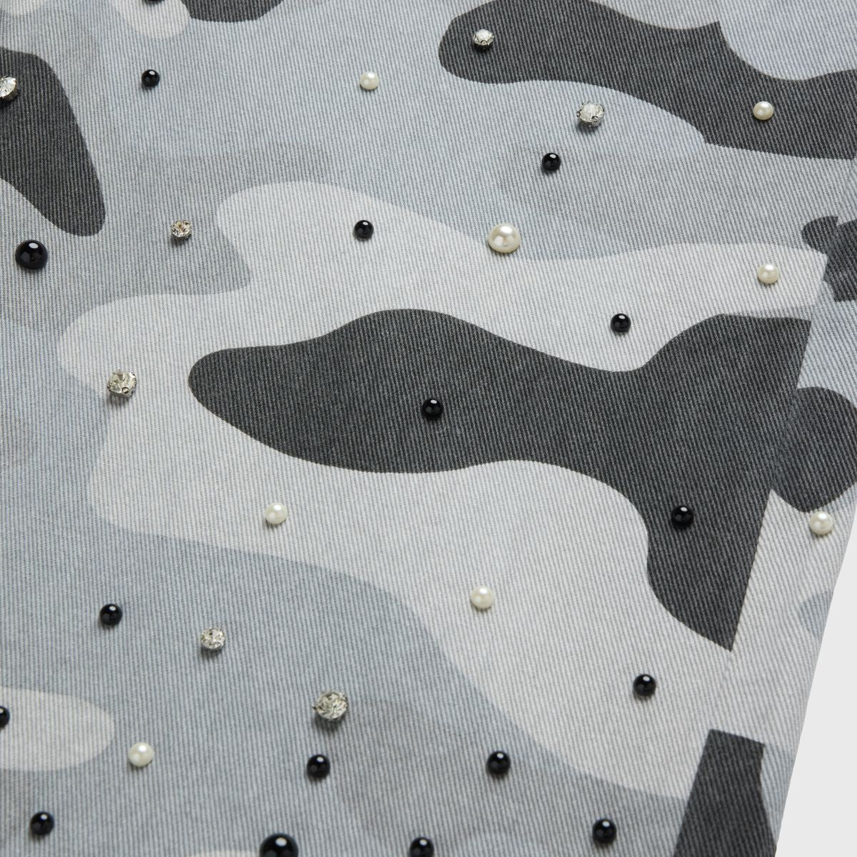 High-quality non-stretch denim shorts with bold snow camouflage print, hand-placed rhinestones, lustrous pearls, and distressed raw hem detail