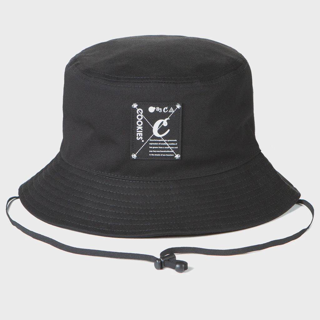 Cookies Key Largo Black Bucket Hat on a beach vacation with palm trees and clear blue water in the background